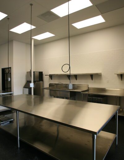 A clean and empty commercial kitchen with stainless steel countertops, shelving, and appliances.