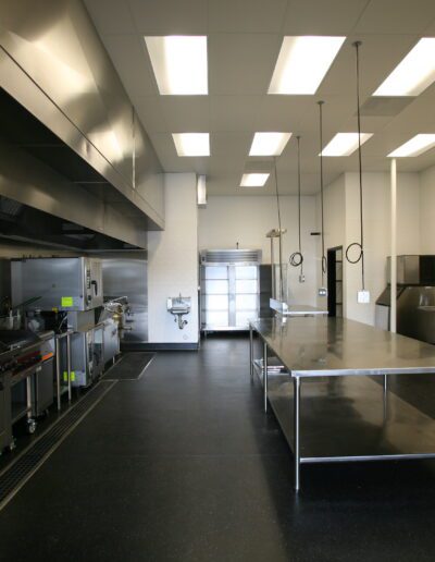 A clean and modern commercial kitchen with stainless steel appliances and work tables.