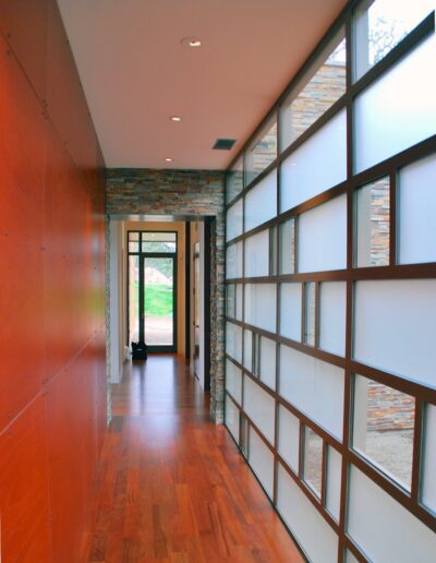 Modern hallway with wooden floor, frosted glass panels, and exposed brick details.