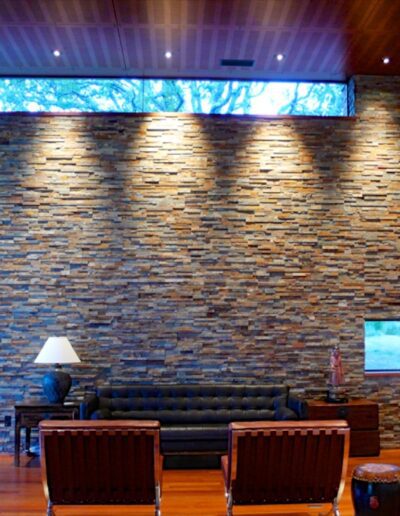 Modern living room with stone wall and floor-to-ceiling windows.