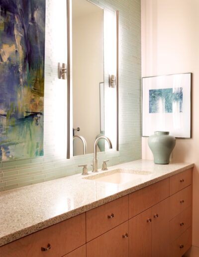 Modern bathroom vanity with a granite countertop, dual sinks, wall-mounted faucets, and framed artwork.