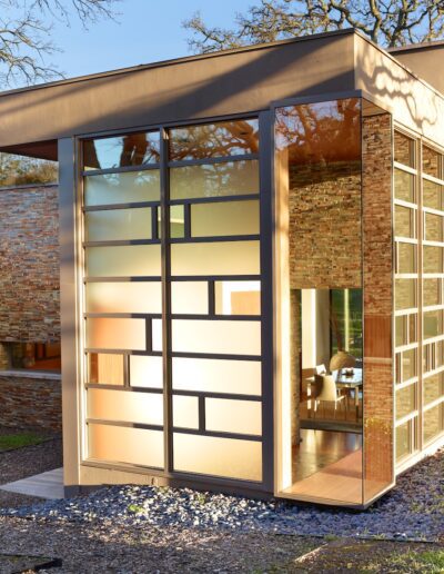 Modern glass extension on a brick house at dusk.