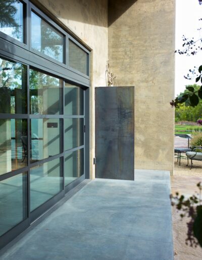 Modern home exterior with large windows and a metal door.