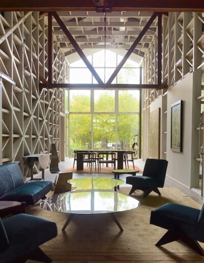 Modern living room featuring geometric wall designs, contemporary furniture, and large windows with a view of greenery.