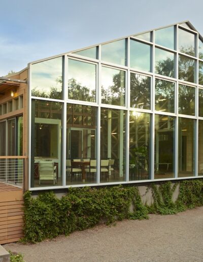 Modern glasshouse with wooden features and an artistic sculpture in the foreground.