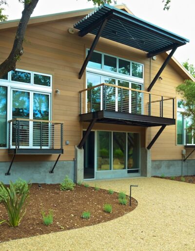 Modern two-story home with a balcony amidst a landscaped garden.