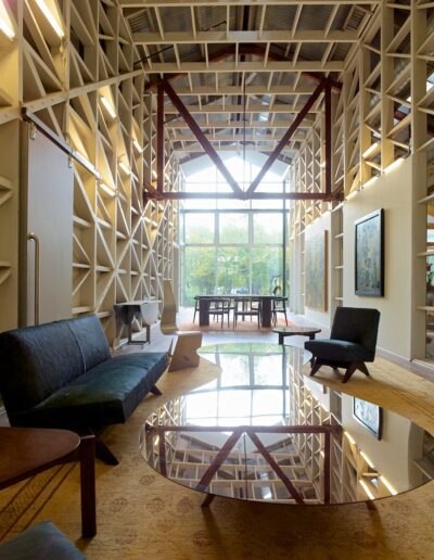 An interior view of a modern room with geometric ceiling design, a reflective table, couches, and art on the walls.