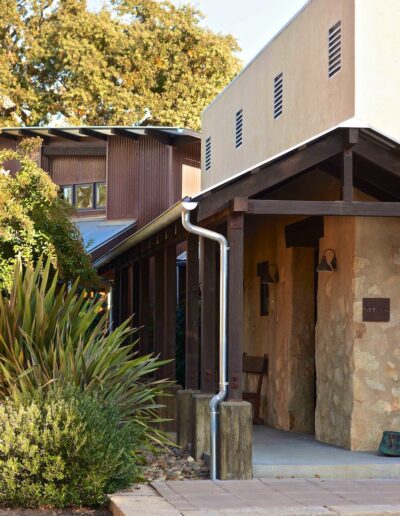 A modern building with an angled gutter, surrounded by vegetation, in the warm light of the setting sun.