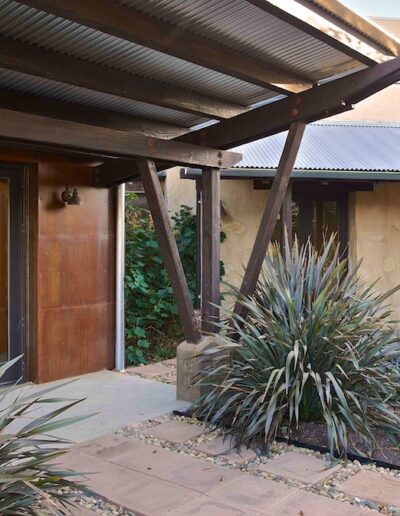 A serene courtyard featuring succulent plants, a paved walkway, and earth-toned buildings with modern wooden accents.