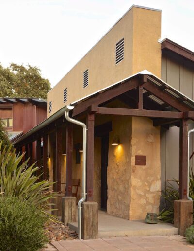 A warm-toned building with a covered entrance and landscaped surroundings at twilight.