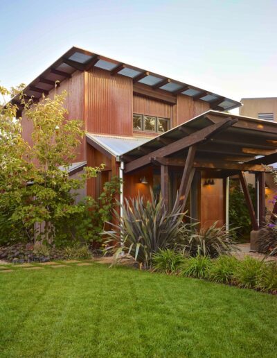 Modern wooden house with landscaped garden and pergola.