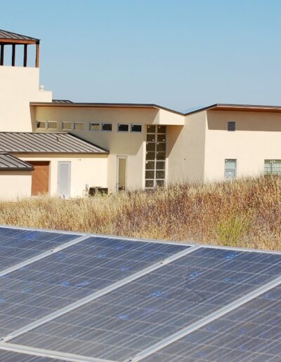Modern house with solar panels in the foreground and rolling hills in the background.