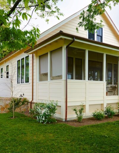 Charming single-story house with a wraparound screened porch and landscaped garden.