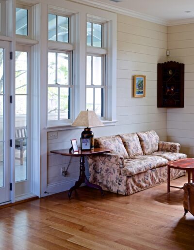 A cozy living room with a floral sofa, a wooden coffee table, and french doors opening to an outdoor area.