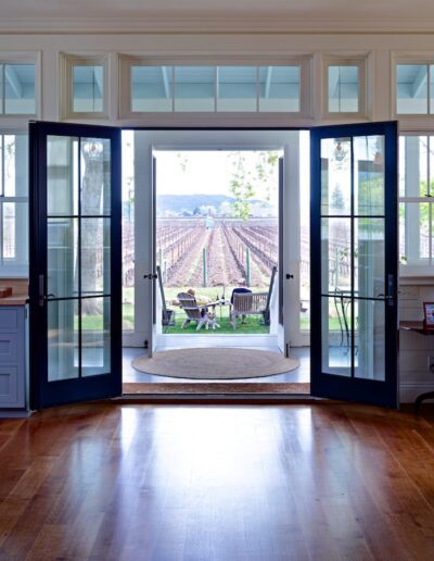 Open french doors leading to a patio overlooking a vineyard.