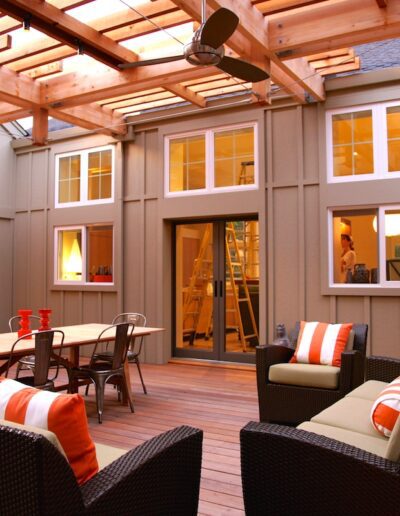 Spacious outdoor patio area with comfortable seating, warm lighting, and a partially covered wooden deck.