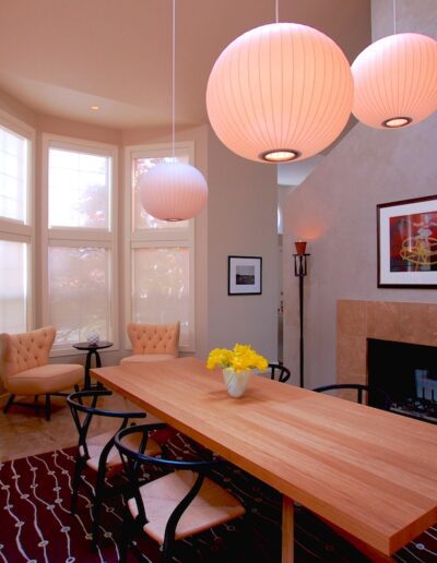 Modern dining room with wooden table, pendant lights, and a fireplace.