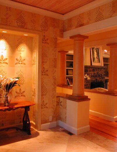 Elegant interior featuring textured wallpaper, wood flooring, and a classic column design with a view into an adjoining room.