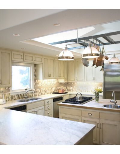 Modern kitchen interior with stainless steel appliances, light wood cabinets, and a marble countertop.
